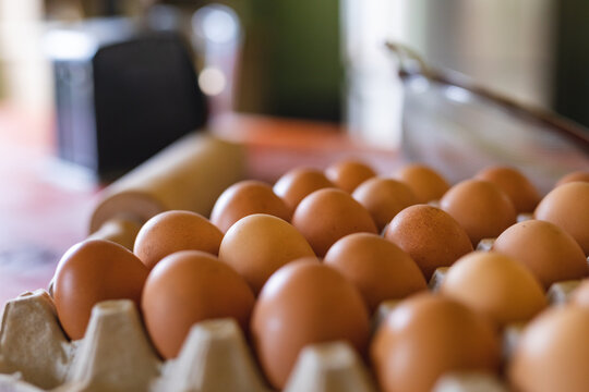 Close-up of fresh brown eggs in carton on table in kitchen at home