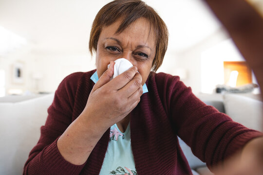Senior woman suffering from runny nose taking online doctor consultation at home