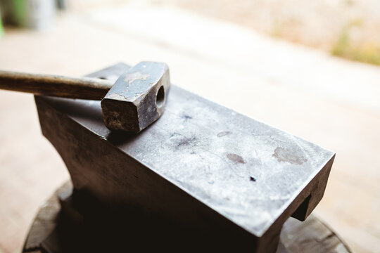 Close-up of hammer with wooden handle on anvil in manufacturing industry