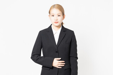 お腹に手を当てるジャケットを着た女性