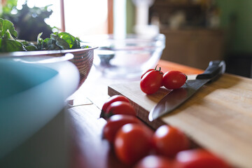 Close-up of fresh red cherry tomatoes with knife on wooden cutting board in kitchen