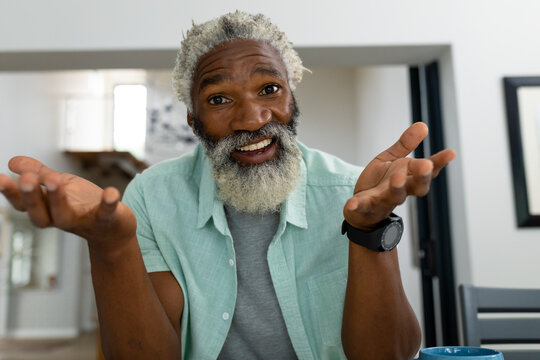 Portrait of happy senior african american man gesturing while sitting in living room at home