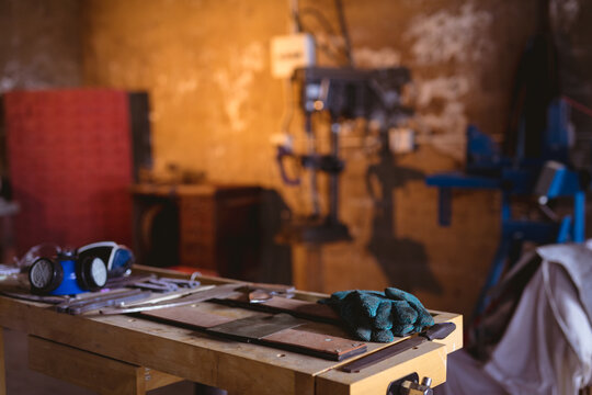 Gas mask with protective gloves and metal on workbench in manufacturing industry