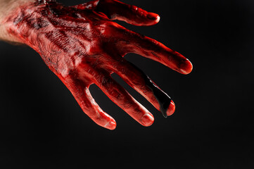 Close-up of a male hand stained with blood on a black background. 