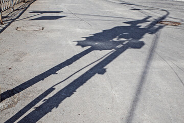 The shadow of a traffic light on the sidewalk on a spring day