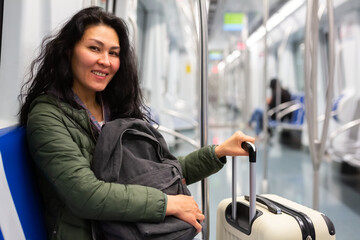 Fototapeta na wymiar Asian woman with suitcase sitting in subway car