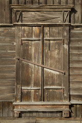 A real authentic vintage closed wooden window in gray brown grunge tones with natural daylight.