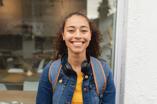 Portrait of smiling young african american woman with wireless headphones in city