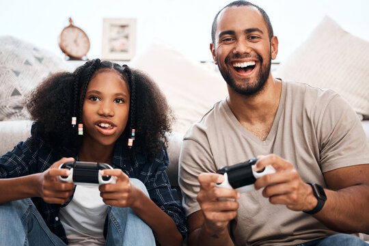 From Playtime To Pro Game Time. Shot Of A Young Girl Playing Video Games With Her Father At Home.