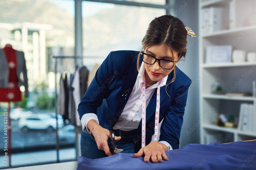 Poster Adjusting the length. Cropped shot of an attractive young fashion designer cutting fabric in her design workshop.