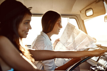 You never know where life will take you. Shot of two friends reading a map on their road trip.