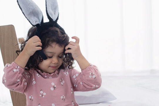 Little happy girl wearing Easter bunny ears on her head holding