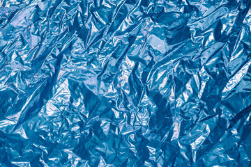 creased shiny metal foil sheet in trendy blue color. Background or backdrop