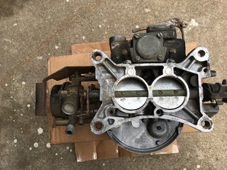 Old dirty two barrel carburetor on cardboard