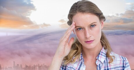Composite image of stressed caucasian woman against sunset sky over cityscape