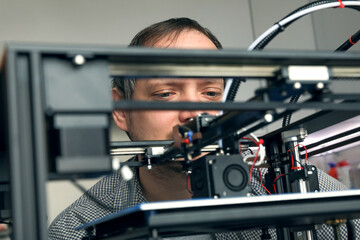 An engineer is setting up a machine for 3D printing, a printer for volumetric printing of parts.