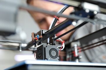 An engineer is setting up a machine for 3D printing, a printer for volumetric printing of parts.