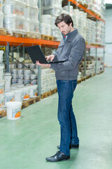storeman using laptop in warehouse - obrazy, fototapety, plakaty