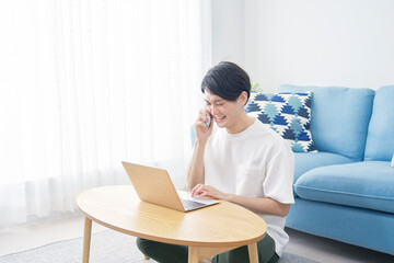男性　スマホ　電話する　ノートパソコン　リビング