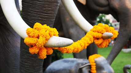 Yellow flower garlands on ivory. Worshiping the revered elephant statue with flowers in Thailand....