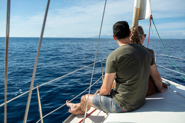 Romantic young couple looking at Atlantic ocean from white sailboat