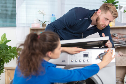 man and woman plumbers fixing washing machine
