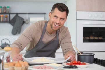 Fototapeta na wymiar happy handsome man cooking in kitchen at home