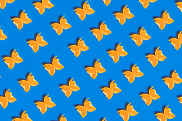 Fototapeta na wymiar A colorful pattern made of tangerine slices looks like a butterfly on a blue background. 