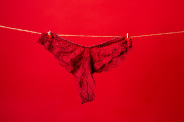 Panties for the girl. Women's panties, sexy lace lingerie on rope. Red thong underpants isolated on red background. Womans sexy underwear. - obrazy, fototapety, plakaty