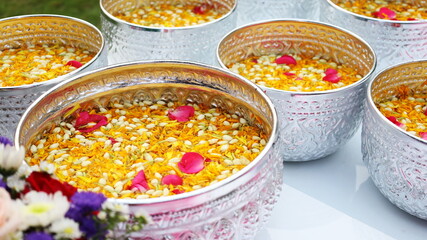 Floating flowers in a silver bowl on the table. Close-up of water in several metals bowls for watering elders or their respected people on Songkran or Thai water festival. Selective focus