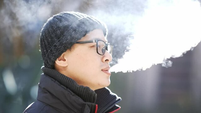 Close-up of man inhaling an e-cigarette vaping device
