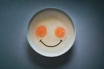Top view of two hard-boiled eggs on a white bowl with a smile inserted below, a concept with a new morning smile..