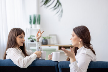 Obraz na płótnie Canvas Three girls discuss news and drink tea in the apartment