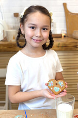 Portrait of a little chef at home in the kitchen. Decorates ginger cookies with icing and powdered sugar for a family holiday