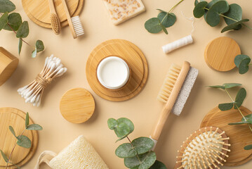 Fototapeta na wymiar Eco cosmetics concept. Top view photo of bamboo foot brush and pumice cream jar soap dental floss toothbrushes hair brush cotton buds green plant leaves and wooden stands on isolated beige background