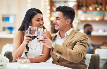 Happy anniversary babe. Cropped shot of an affectionate young couple making a celebratory toast while sitting in a restaurant.