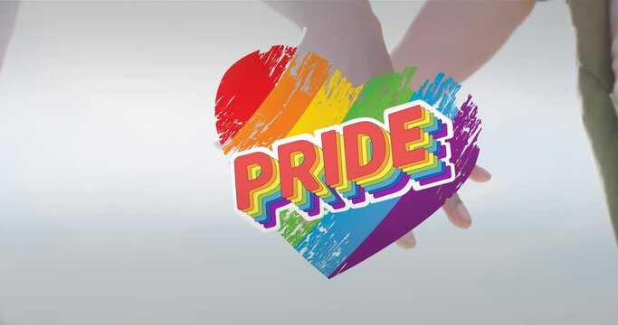 Animation of rainbow heart and pride over hands of caucasian lesbian couple