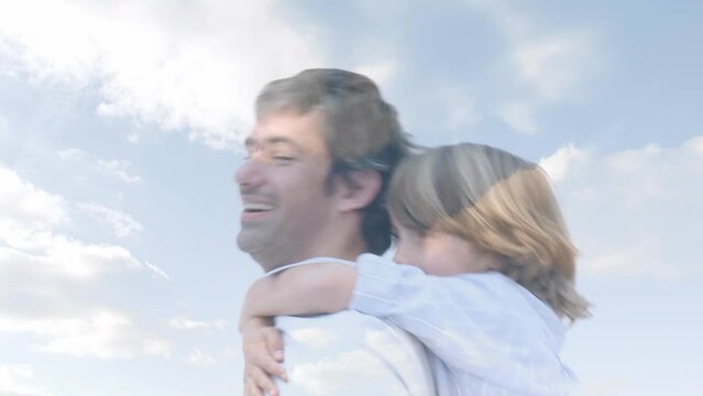 Animation of clouds over happy caucasian father and son having fun outdoors