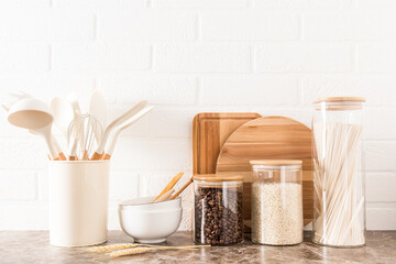 various kitchen utensils on a marble countertop in a modern kitchen. the concept of decor against the background of a white brick wall.