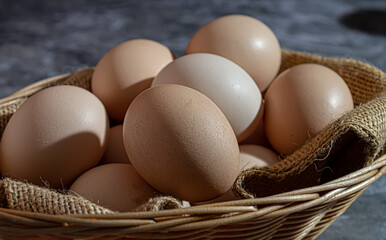 Close-up of raw chicken eggs in a basket on a gray marble background