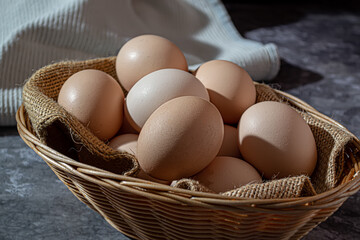 Close-up of raw chicken eggs in a basket on a gray marble background