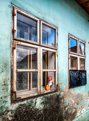Baby doll in window with broken glass on ruined house