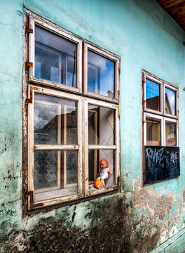 Baby Doll In Window With Broken Glass On Ruined House