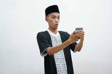 Muslim Asian man showing excited face expression when looking to his mobile phone