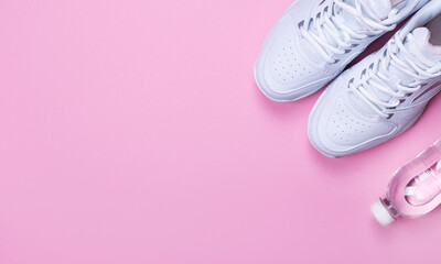 Fototapeta na wymiar White sneakers and a bottle of water on a pink background. Concept, jogging, running, fitness, cross-fit. Morning running. Banner. Flat bed, top view