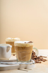 Cold dairy coffee drink with milk, whipped cream. Foamy frappe, latte, cappuccino, on a cream background, space for text. Summer cold coffee cocktail
