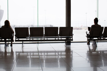 Female sitting on bench seat waiting in front of large window
