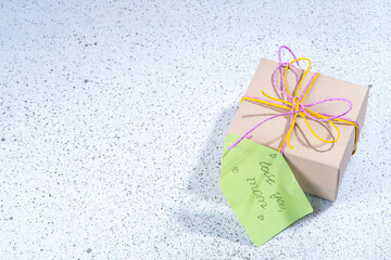 Mother day greeting card background with present and flowers. Gift box with festive ribbon, tag Love you mom, spring bloom flowering branches bouquet flatlay copy space