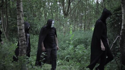 A cult of evil hooded druids are walking in the woods and about to perform a sacrifice ritual