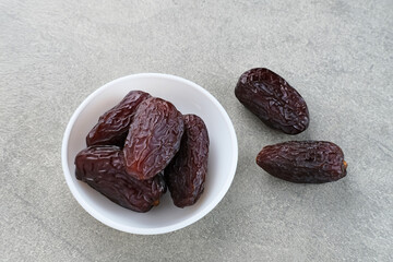 Fresh Medjool Dates Fruit served in small plate on grey background. Close up. Ramadan kareem. 
